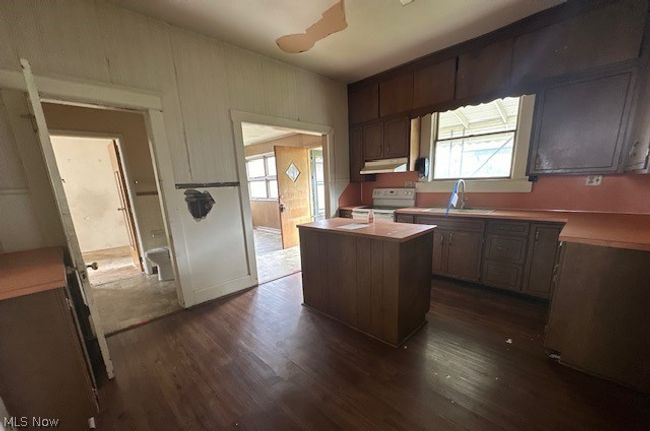 Kitchen with white range, sink, dark wood-type flooring, and a kitchen island | Image 16