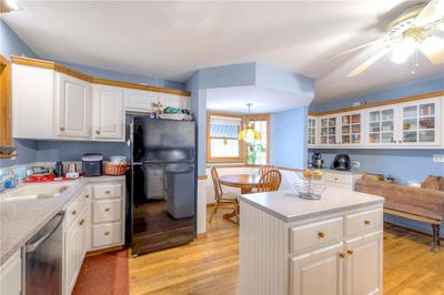 Kitchen featuring stainless steel dishwasher, black refrigerator, white cabinetry, and light hardwood / wood-style flooring | Image 3