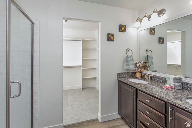 Full bathroom with wood finished floors, a shower stall, double vanity, a sink, and baseboards | Image 19
