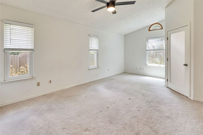 Carpeted spare room featuring lofted ceiling, a textured ceiling, and ceiling fan | Image 11