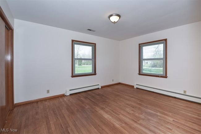 Spare room with a baseboard heating unit, baseboards, visible vents, and light wood-type flooring | Image 33