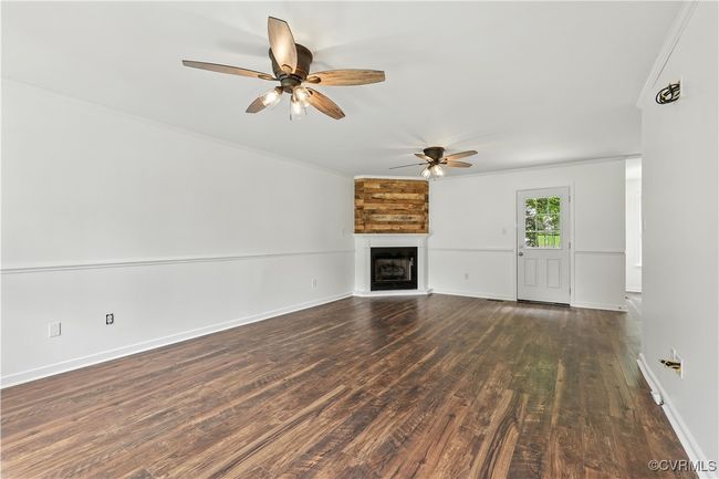 Large room featuring ceiling fan, ornamental molding, Laminate-style floors, and a corner gas fireplace | Image 6