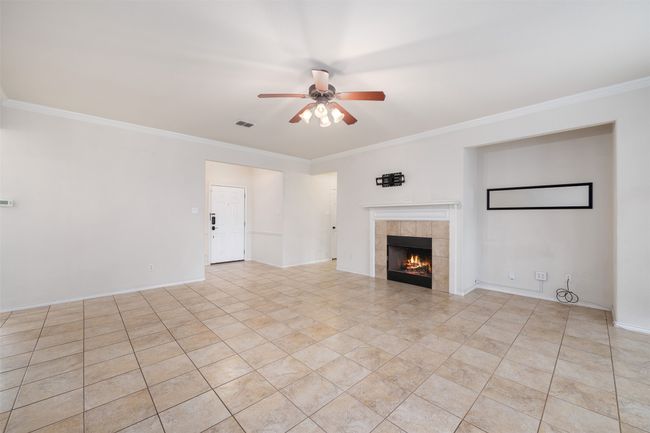 crown molding, a tiled fireplace, and a ceiling fan | Image 4