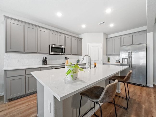 Kitchen with a sink, a kitchen island with sink, visible vents, appliances with stainless steel finishes, and gray cabinets | Image 6