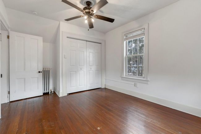 Unfurnished bedroom featuring radiator, dark wood-style flooring, a closet, baseboards, and a ceiling fan | Image 39