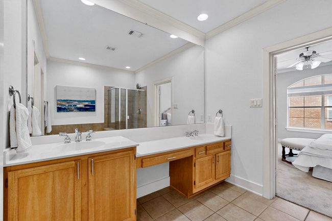 Full bathroom with crown molding, double vanity, a shower stall, tile patterned floors, and a ceiling fan | Image 21