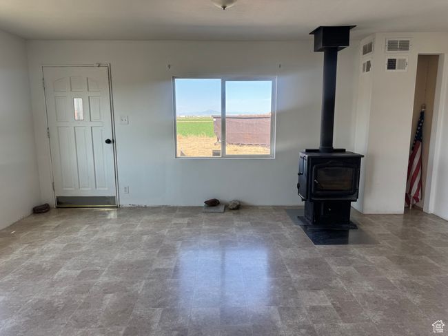 Unfurnished living room featuring visible vents and a wood stove | Image 27