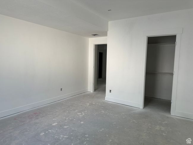 Unfurnished bedroom with concrete floors, baseboards, a walk in closet, and a closet | Image 30