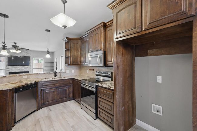 Kitchen featuring appliances with stainless steel finishes, a sink, a ceiling fan, and decorative backsplash | Image 8