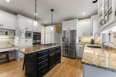 The well-designed kitchen includes new appliances, granite countertops, a center island, and an eat-in dining area, making it both functional and elegant. | Image 3