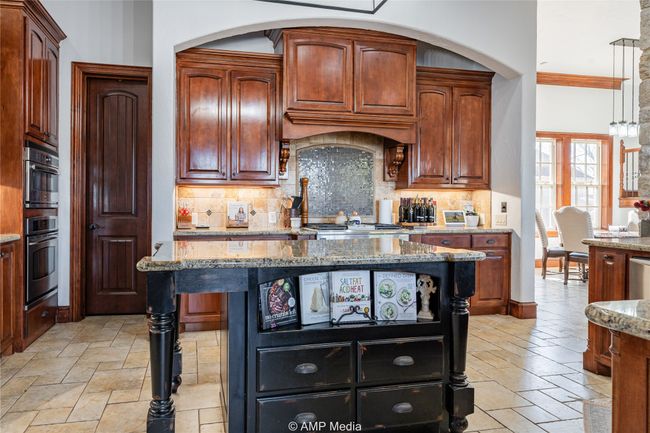 Kitchen with backsplash, stone counters, and a center island | Image 13