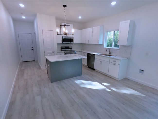 Kitchen featuring a sink, a center island, tasteful backsplash, appliances with stainless steel finishes, and white cabinetry | Image 5