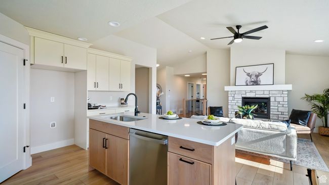 Kitchen featuring stainless steel dishwasher, light wood-style floors, light countertops, open floor plan, and vaulted ceiling | Image 11