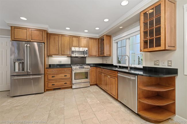 Kitchen featuring appliances with stainless steel finishes, glass insert cabinets, brown cabinets, recessed lighting, and ornamental molding | Image 8