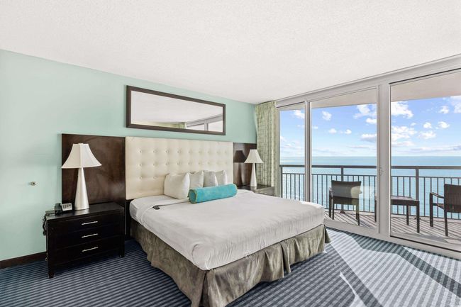 Bedroom featuring a textured ceiling, a wall of windows, a water view, access to outside, and dark carpet | Image 18