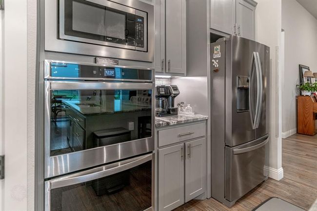 Kitchen with stainless steel appliances, a kitchen breakfast bar, separate washer and dryer, tasteful backsplash, and dark wood-type flooring | Image 9