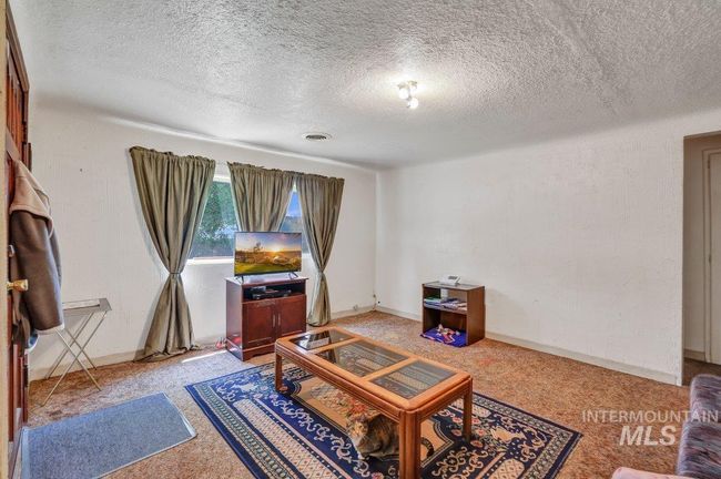 Living room with a textured ceiling and light carpet | Image 13