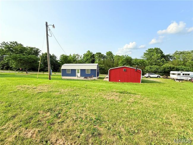 View of grassy yard with an outbuilding, a pole building, and view of wooded area | Image 51