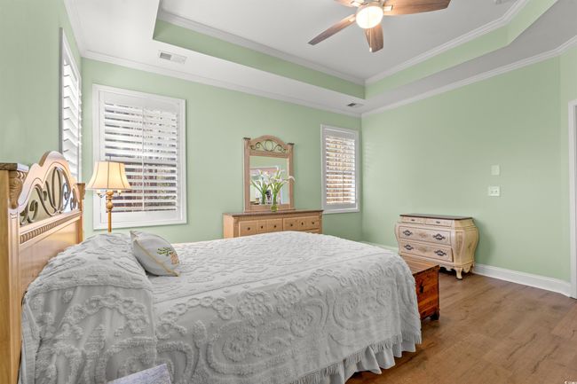 Bedroom with visible vents, wood finished floors, crown molding, and a raised ceiling | Image 19