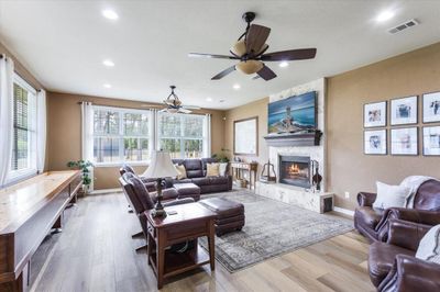 Living room featuring a high end fireplace, a textured ceiling, ceiling fan, and light hardwood / wood-style floors | Image 3