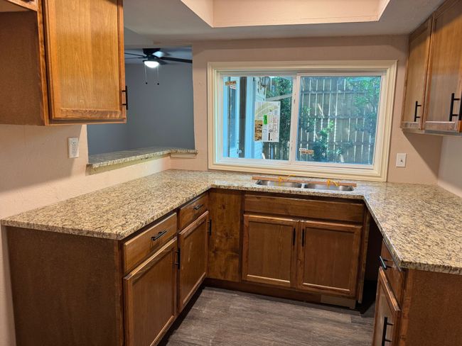 Kitchen featuring a ceiling fan, light stone counters, and dark wood-type flooring | Image 5