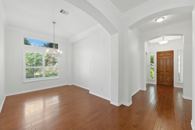 Entry hall with arched walkways, fresh paint, wood flooring. There is a glass door behind the beautiful wood door to allow more natural light in. | Image 17