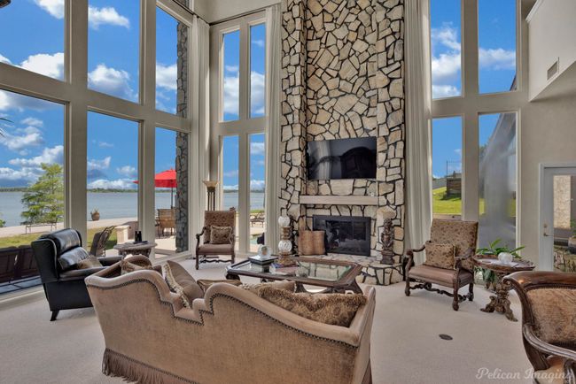 Carpeted living area with a water view, a fireplace, and a towering ceiling | Image 10