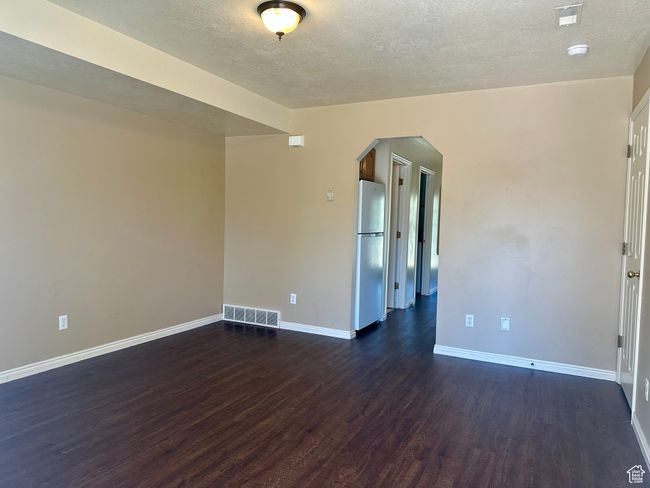 Living room with arched walkways, upgraded floors, a textured ceiling, and a smoke detector | Image 7