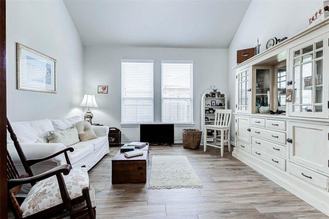 This thoughtfully designed space offers versatility—perfect as a formal dining room, living area, or home office. A vaulted ceiling adds architectural interest, while two floor-to-ceiling windows bathe the room in natural light. | Image 12