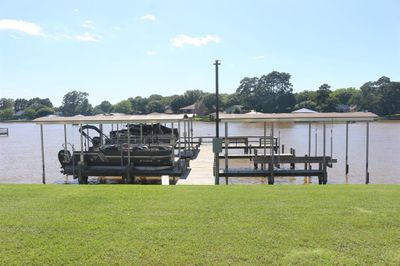 This photo features a well-maintained dock with a covered boat lift, overlooking a tranquil lake with lush greenery, offering an ideal setting for aquatic recreation and relaxation. | Image 2