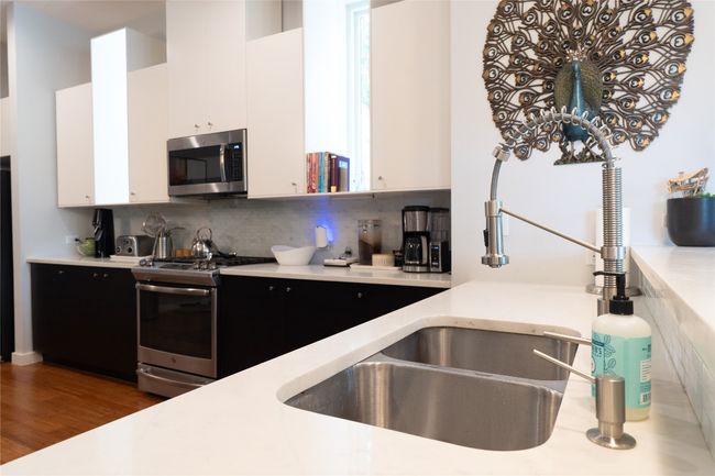 Kitchen with appliances with stainless steel finishes, dark cabinets, white cabinetry, and light countertops | Image 27