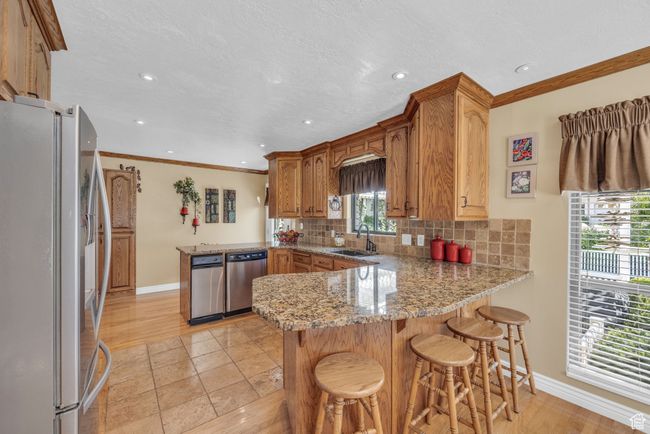Kitchen featuring appliances with stainless steel finishes, a peninsula, baseboards, backsplash, and a sink | Image 10