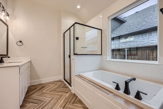 Bathroom with a shower stall, baseboards, vanity, and a garden tub | Image 19