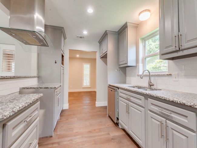 Kitchen featuring island range hood, a sink, gray cabinetry, light wood finished floors, and decorative backsplash | Image 9