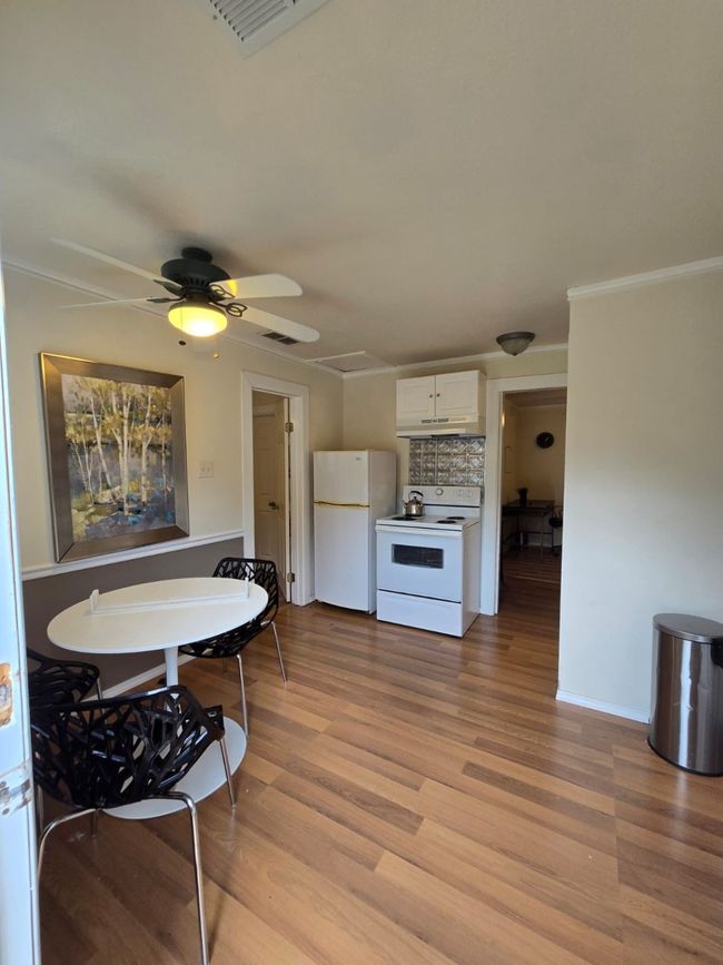 Kitchen featuring white cabinetry, white appliances, light wood-type flooring, light countertops, and decorative backsplash | Image 23
