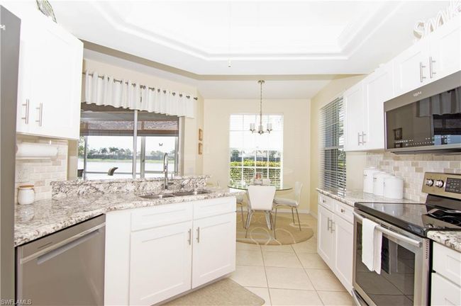 Kitchen offers ample light from 2 windows and a sliding glass door that leads to the screened lanai. | Image 12