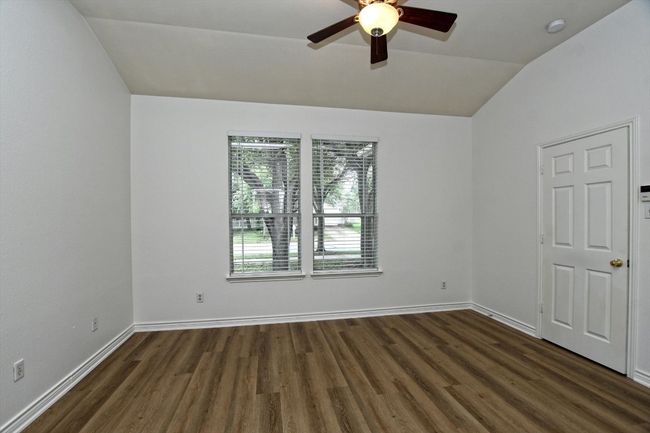 Empty room featuring vaulted ceiling, ceiling fan, dark wood-style floors, and a smoke detector | Image 11