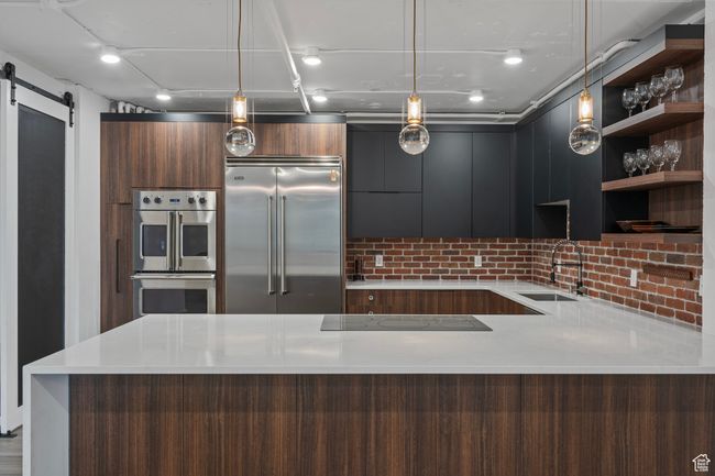 Kitchen with hanging light fixtures, appliances with stainless steel finishes, sink, and a metal barn door | Image 9