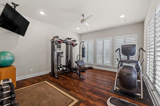 Exercise room featuring wood finished floors, visible vents, a ceiling fan, and a wealth of natural light | Image 25