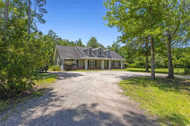 New england style home featuring curved driveway, covered porch, and brick siding | Image 5