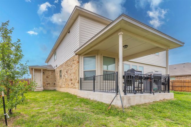 Rear view of property featuring fence, a yard, and stone siding | Image 37