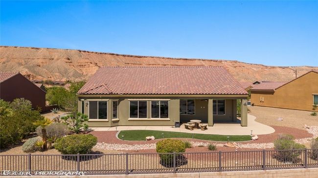 Rear view of property featuring stucco siding, a mountain view, a fenced front yard, a patio area, and a tiled roof | Image 62