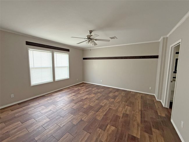 Empty room featuring crown molding, dark wood-style flooring, and a ceiling fan | Image 16