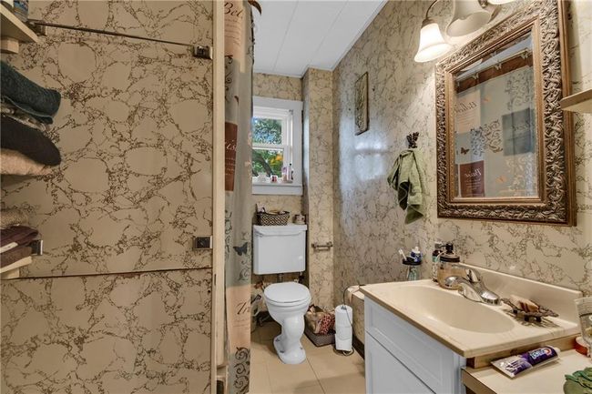 Bathroom with vanity, a shower stall, tile patterned flooring, and wallpapered walls | Image 10