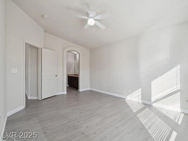 Empty room featuring light wood finished floors, ceiling fan, and arched walkways | Image 10