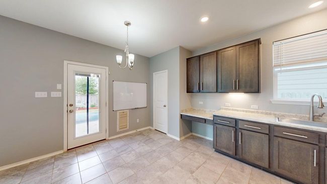 Kitchen with a sink, baseboards, a chandelier, and dark brown cabinets | Image 19