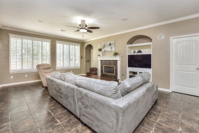 The large light-filled family room has a gas log fireplace, plantation shutters, and built-in cabinetry. | Image 8