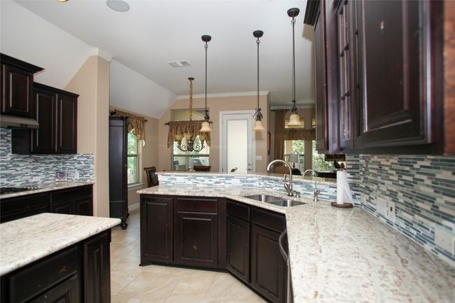 Kitchen featuring a sink, decorative backsplash, plenty of natural light, a peninsula, and vaulted ceiling | Image 8