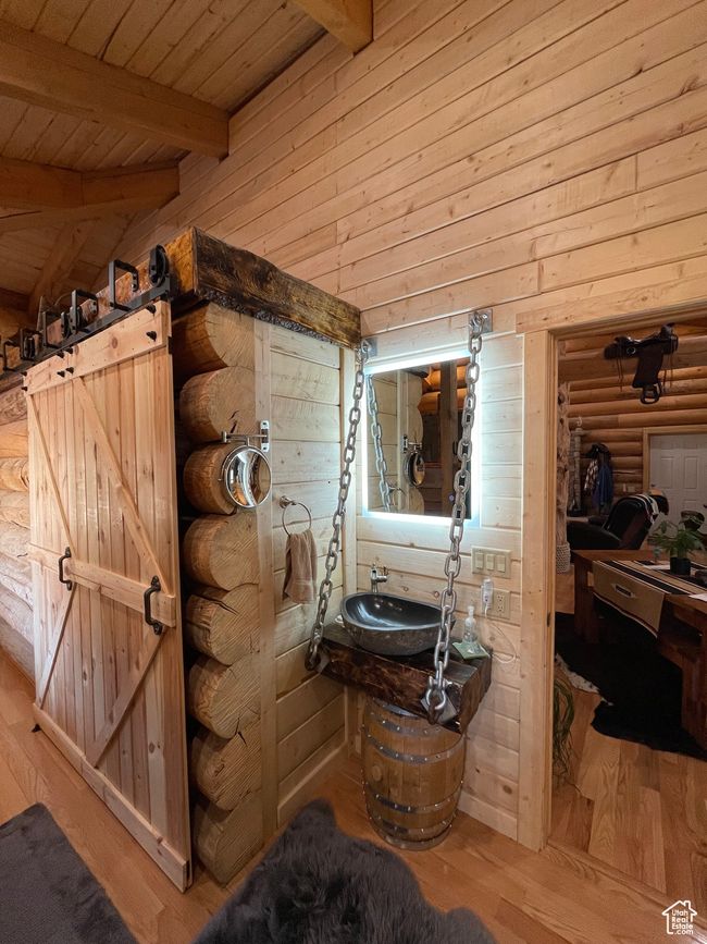 Bathroom featuring wooden ceiling, a sink, vaulted ceiling with beams, wood finished floors, and rustic walls | Image 83