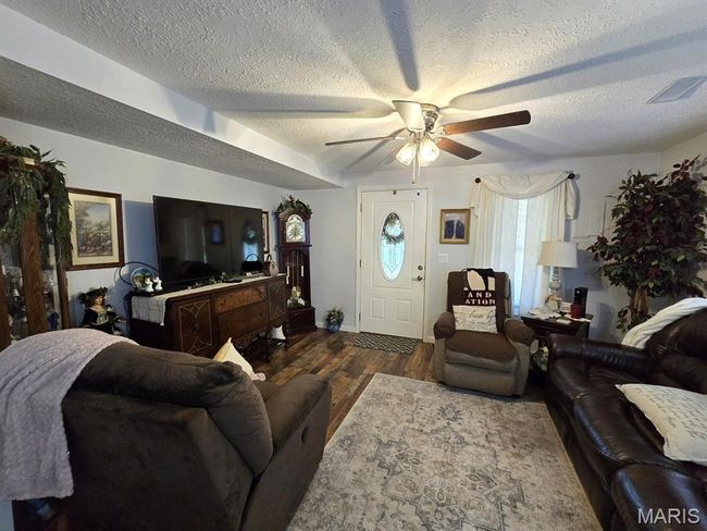 Living room featuring ceiling fan, a textured ceiling, and wood finished floors | Image 4